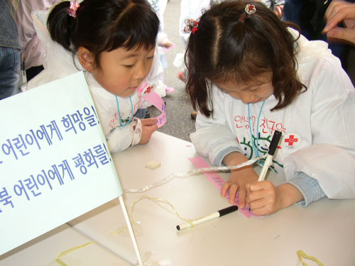 한 어린이가 '평화의 리본'에 이라크 어린이에게 전하는 말을 적고 있다. 